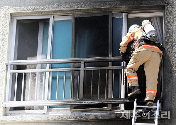 13일 오후 1시15분쯤 제주시 이호동의 4층짜리 빌라 2층 화재로 2명의 사상자가 발생했다. 큰 불길이 잡히자 소방관이 거실 창문을 통해 내부에 진입하고 있다.