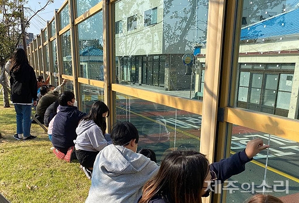 27일 서귀포시 예래초등학교 5~6학년 학생들이 학교 주변 142m 투명 방음벽에 조류 충돌 방지를 위한 점자 스티커를 부착하고 있다. [사진제공-녹색연합]