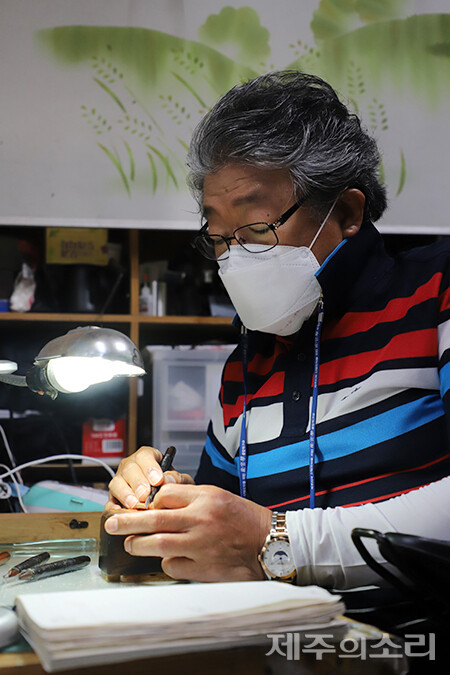 작업에 몰두하고 있는 박효민 훈민당 대표. 그의 작업대 위에는 확대경과 조명, 40년이 넘은 제작 도구들이 늘 자리하고 있다. ⓒ제주의소리