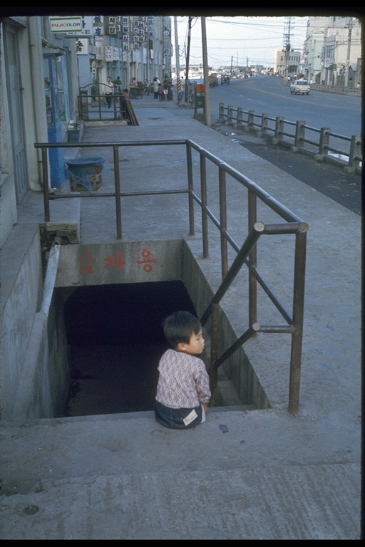 1971년 8월~10월 사이에 제주시 일도1동 산짓물 입구에서 어린 아이가 앉아있다. / 사진=이토 아비토, 제주학아카이브