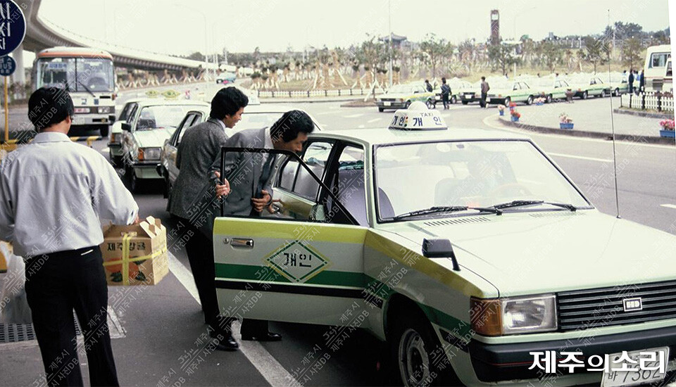 1980년대 제주국제공항에서 관광객들이 개인택시에 탑승하는 모습. 개인택시는 당시 관광산업 발전에 큰 역할을 했다. [사진출처-제주시 사진DB]<br>