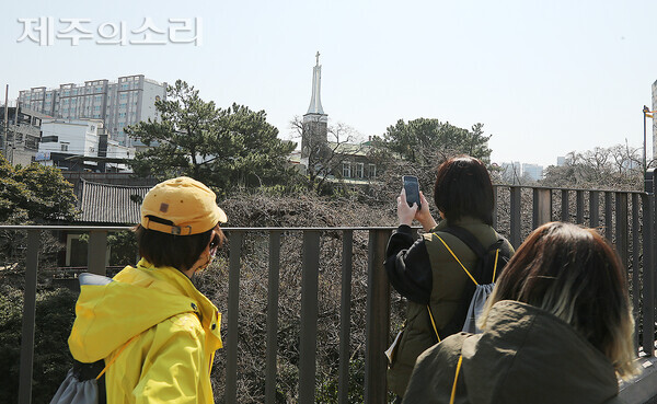 부처(왼쪽 기와건물)와 예수(가운데 십자가 건물)가 함께하는 모습을 사진으로 남기는 모습. ⓒ제주의소리