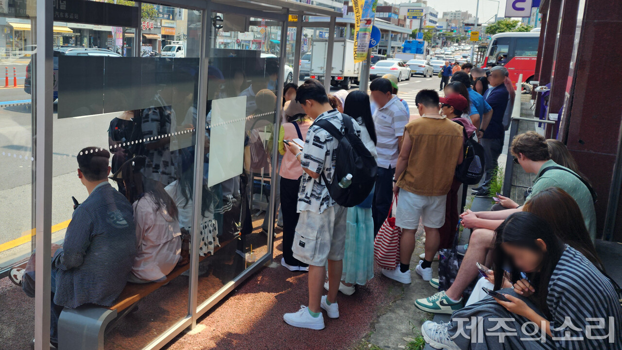 제주버스터미널 가로변 정류장에 관광객들이 대기 중인 모습. 버스 감차와 섬식정류장, 양문형버스 도입으로 관광객들은 버스 탑승에 혼란을 빚었다. ⓒ제주의소리