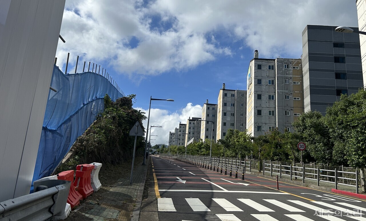 옹벽을 허물 수 없어 펜스 대신 설치된 파란 방진막. 바람을 타고 날아드는 비산먼지를 막기에는 역부족으로 보인다. ⓒ제주의소리