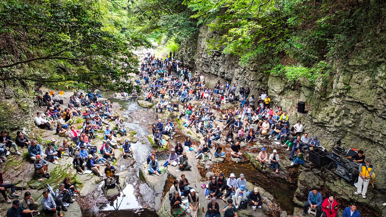 2025 안덕계곡예술제가 지난 10월 18일 제주 안덕계곡 일원에서 열렸다. 가을을 맞은 안덕계곡의 상록수림과 맑은 물소리를 배경으로 계곡 곳곳에 자연스럽게 둘러 앉은 2025 안덕계곡예술제 청중들 모습<br>